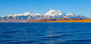 Snow-Capped Mount Kailash Rising Above the Deep Blue Waters of Lake Mansarovar HD wallpaper