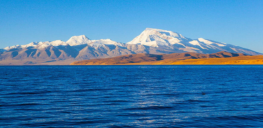 Snow-Capped Mount Kailash Rising Above the Deep Blue Waters of Lake Mansarovar HD wallpaper