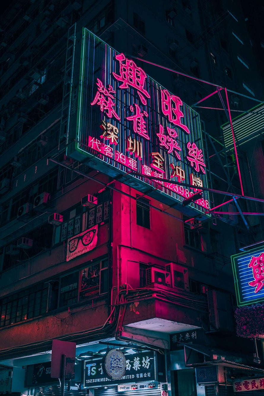 Neon-lit Hong Kong street corner at night with vibrant pink and blue Chinese signage on urban buildings HD phone wallpaper