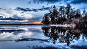 Serene Winter Lake at Dusk with Pine Tree Reflections and Dramatic Clouds HD wallpaper