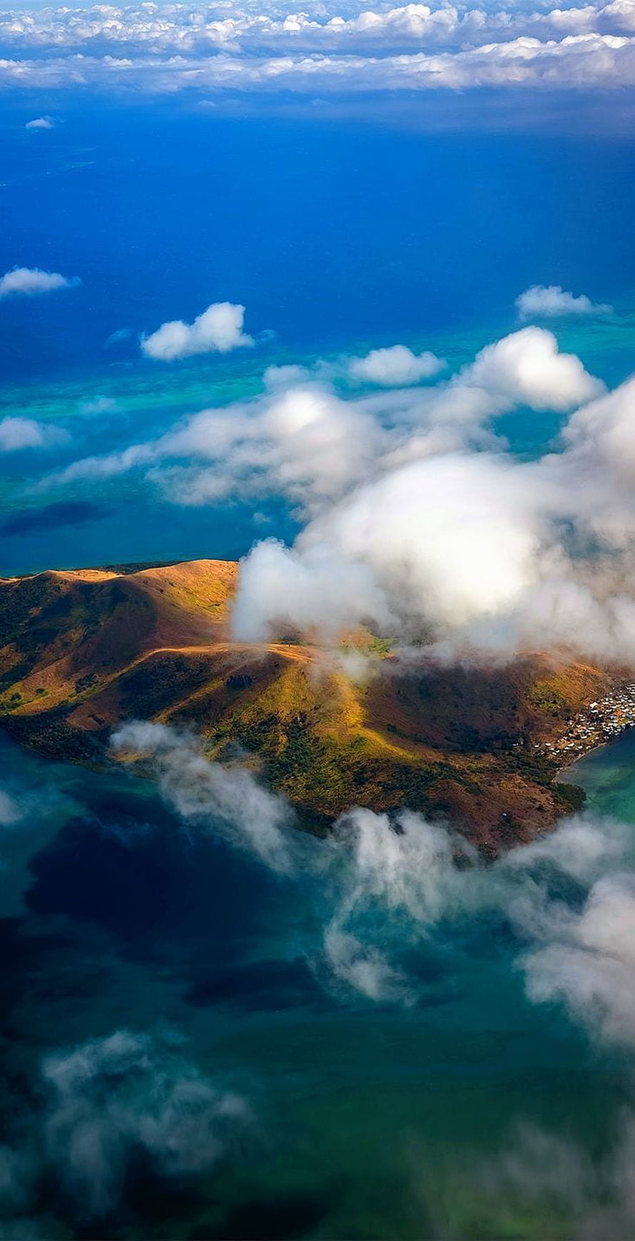 Aerial View of a Misty Island Mountain Rising Above Turquoise Ocean Waters HD phone wallpaper
