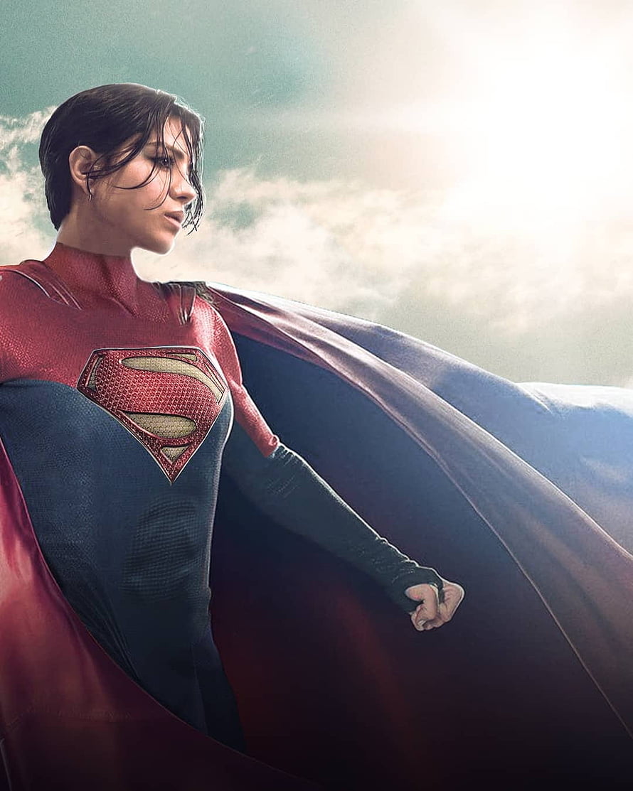 Supergirl in red and blue suit with flowing cape against bright sky HD phone wallpaper