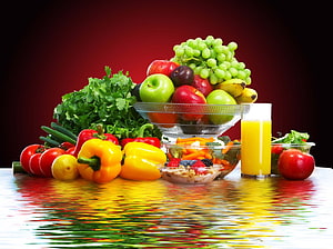 Vibrant Fresh Fruit and Vegetable Arrangement with Orange Juice on Reflective Surface HD wallpaper