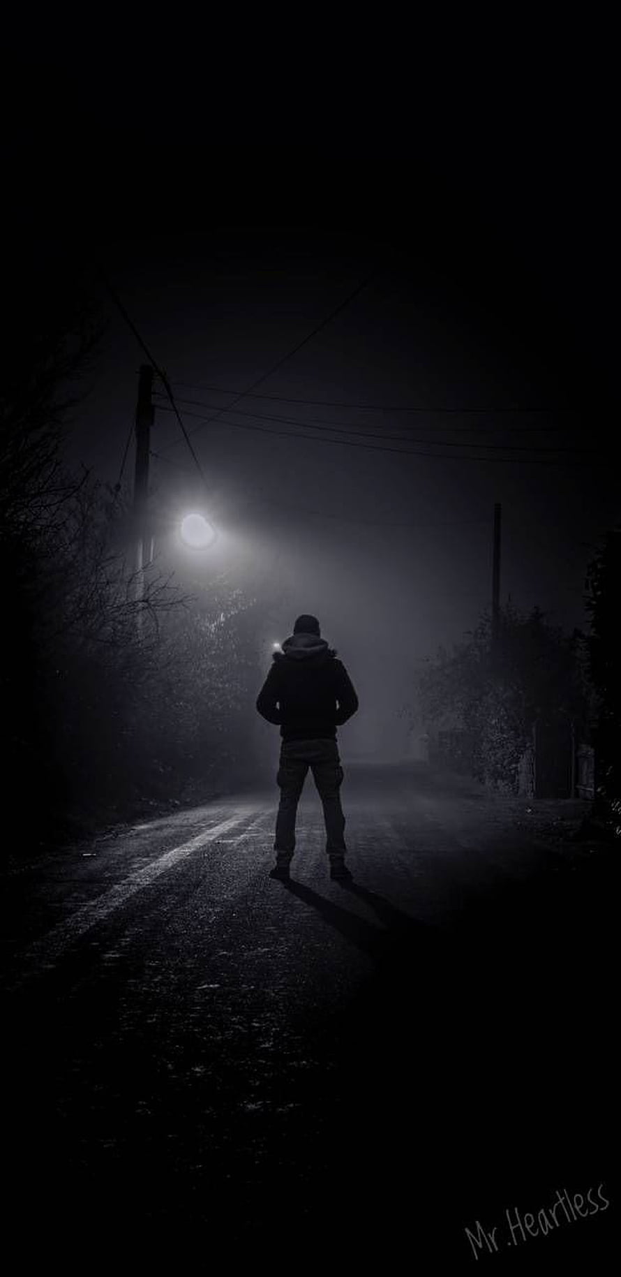 Lonely figure standing on a dark foggy road at night under a streetlight HD phone wallpaper