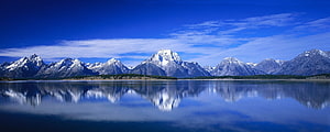 Snow-Capped Mountain Range Reflected in a Calm Alpine Lake Under a Blue Sky HD wallpaper