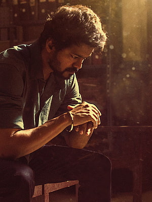 Dhanush in a contemplative pose with warm cinematic lighting and a moody atmosphere HD phone wallpaper
