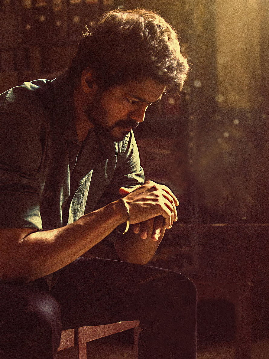 Dhanush in a contemplative pose with warm cinematic lighting and a moody atmosphere HD phone wallpaper