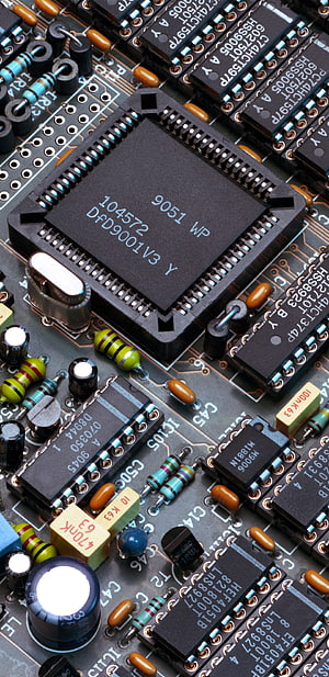 Close-up of a Printed Circuit Board with Microchips, Resistors, and Capacitors HD phone wallpaper
