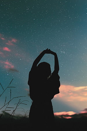 Silhouette of a person stretching arms under a starry night sky with pink clouds HD phone wallpaper
