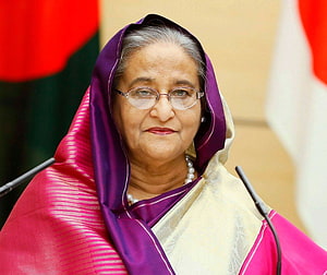Sheikh Hasina in a purple and pink sari with glasses and pearl necklace at a formal event HD wallpaper