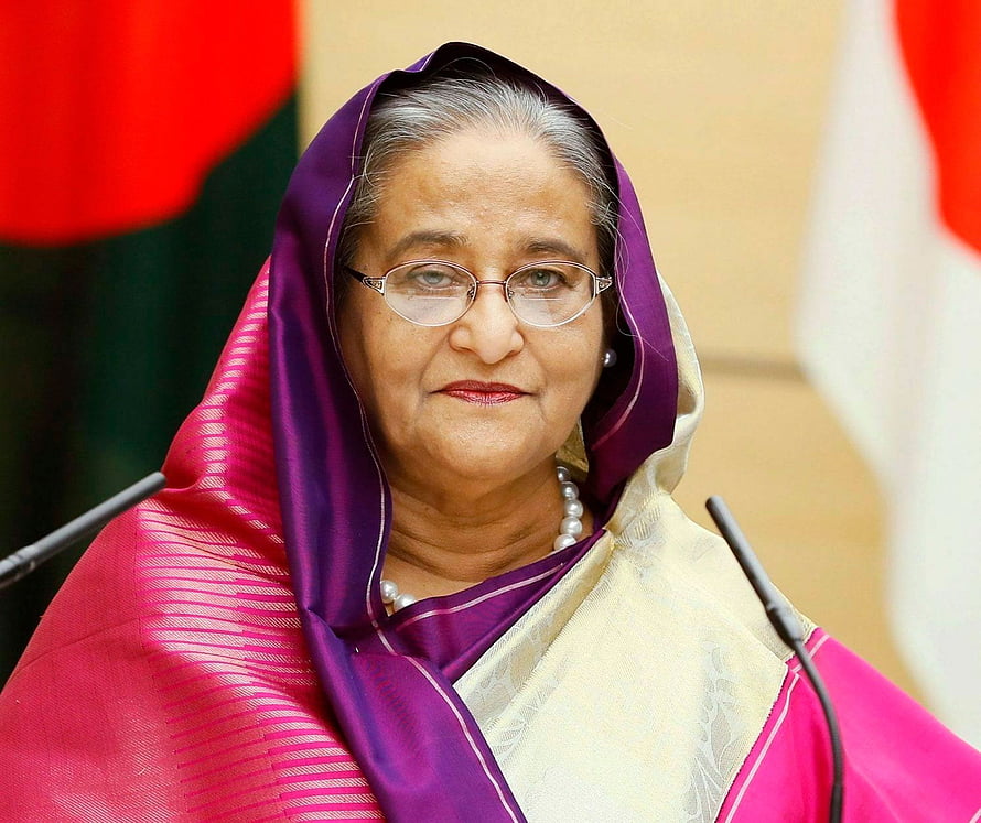 Sheikh Hasina in a purple and pink sari with glasses and pearl necklace at a formal event HD wallpaper