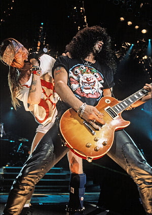 Slash and Axl Rose performing live on stage with electric guitar and microphone HD phone wallpaper