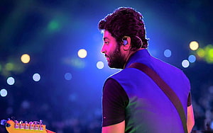 Arijit Singh performing live on stage with electric guitar under blue concert lighting HD wallpaper