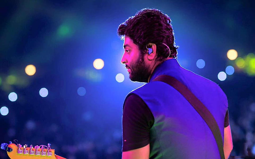Arijit Singh performing live on stage with electric guitar under blue concert lighting HD wallpaper