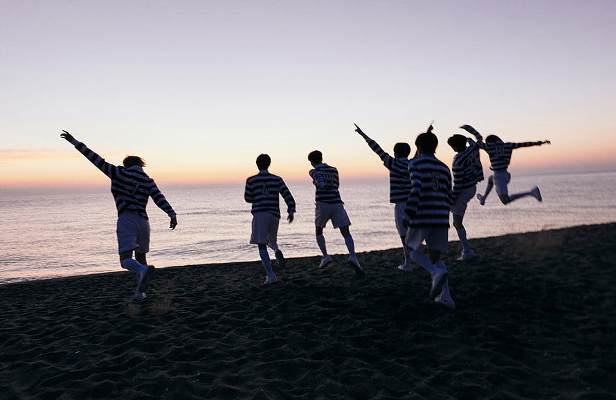 Silhouettes of soccer players celebrating victory on a sandy beach at sunset HD wallpaper