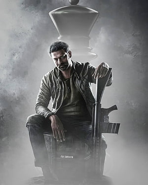 Prabhas as Salaar in gritty monochrome action pose with rifle and chess piece HD phone wallpaper