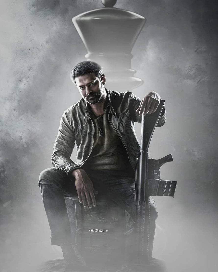 Prabhas as Salaar in gritty monochrome action pose with rifle and chess piece HD phone wallpaper