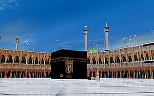 The Kaaba in Mecca, Saudi Arabia, surrounded by the Grand Mosque under a clear blue sky HD wallpaper
