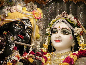 Radiant Radha Krishna idols adorned with flowers and jewelry in a divine temple setting HD wallpaper
