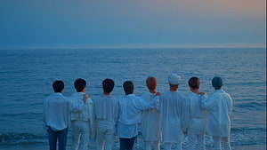 BTS members standing together on a beach looking out at the ocean during twilight HD wallpaper
