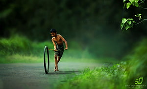 Young boy rolling a bicycle wheel on a rural road in Bangladesh HD wallpaper