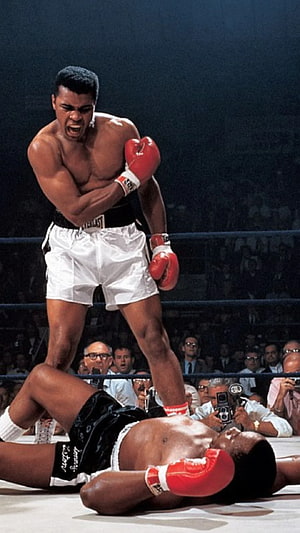 Muhammad Ali standing over fallen opponent in boxing ring HD phone wallpaper