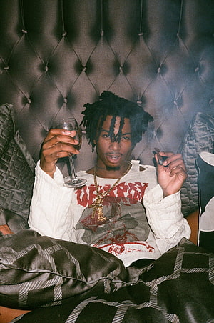 Playboi Carti Holding Wine Glass and Cigar in Tufted Headboard Setting HD phone wallpaper