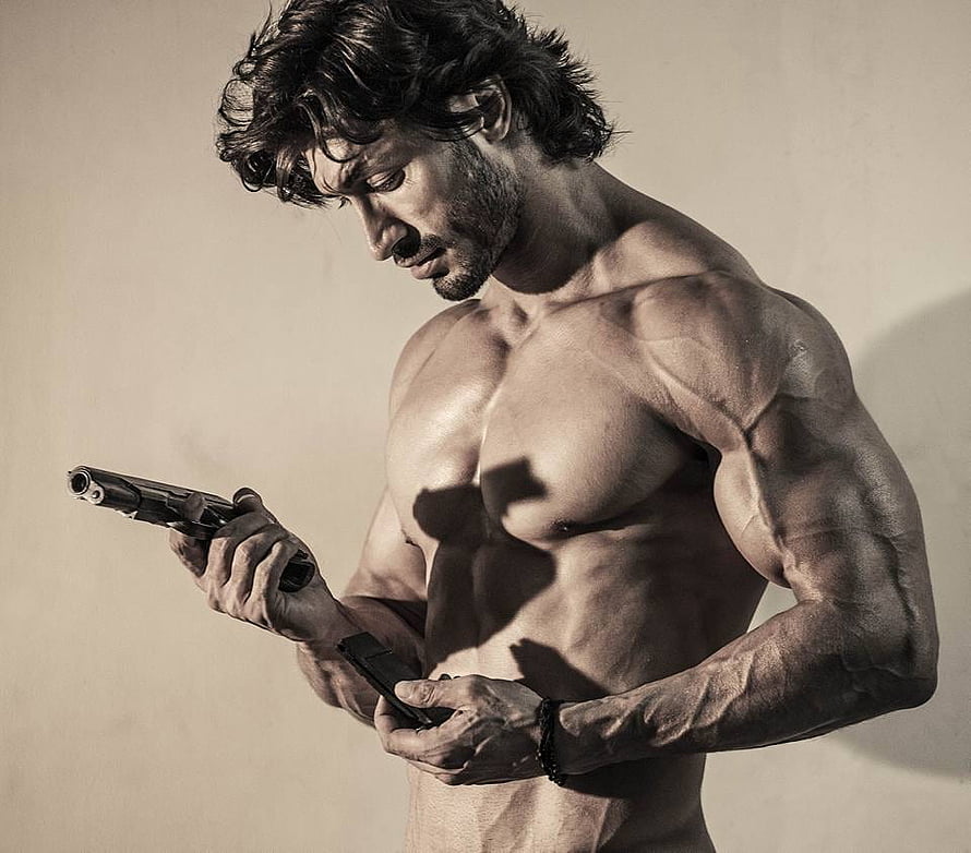 Vidyut Jammwal shirtless muscular portrait holding a pistol in dramatic sepia lighting HD wallpaper
