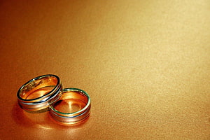 Two Gold Wedding Bands on a Textured Golden Surface HD wallpaper