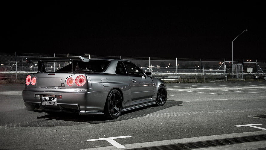 Nissan Skyline GT-R R34 Rear Three-Quarter View in Nighttime Parking Lot HD wallpaper
