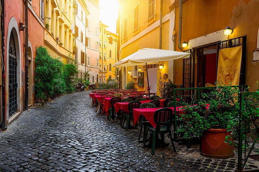 Charming Cobblestone Alley with Outdoor Cafe Tables and Warm Sunset Lighting HD wallpaper