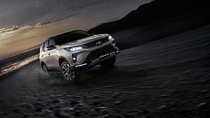 Toyota Fortuner Legender SUV Driving on Gravel Road at Dusk with Dramatic Skyline HD wallpaper