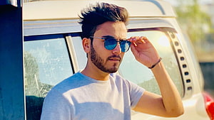 Elvish Yadav Wearing Blue Sunglasses in Front of a White Van HD wallpaper
