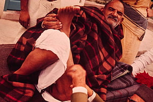 Neem Karoli Baba Reclining in a Red Plaid Blanket with Devotees HD wallpaper