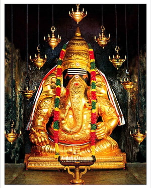 Golden Ganesha Statue in Cave Temple with Hanging Oil Lamps and Flower Garlands HD phone wallpaper