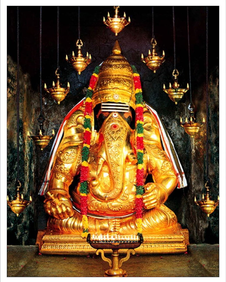 Golden Ganesha Statue in Cave Temple with Hanging Oil Lamps and Flower Garlands HD phone wallpaper