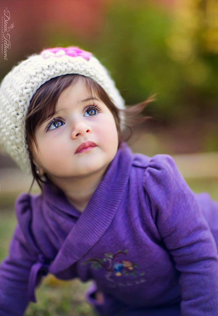 Adorable Toddler Girl in Purple Sweater and White Knit Hat Looking Up Outdoors HD phone wallpaper