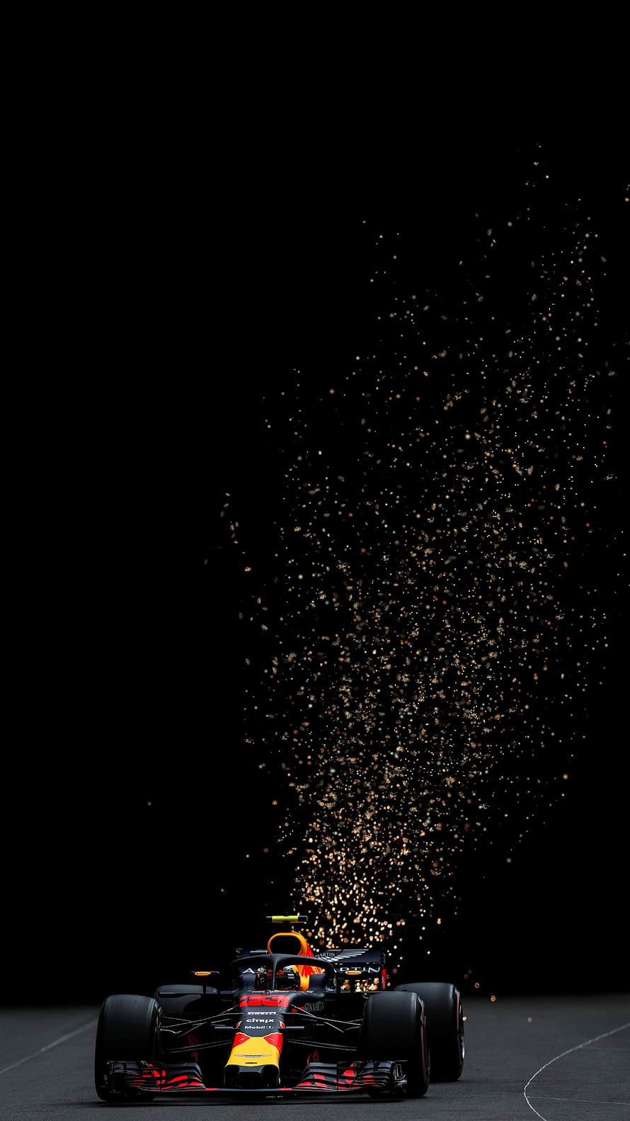 Red Bull Racing Formula 1 car speeding through a dramatic burst of golden sparks on a dark track HD phone wallpaper