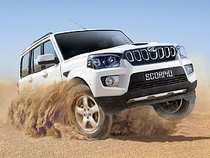 White Mahindra Scorpio SUV drifting on dusty desert terrain kicking up sand HD wallpaper