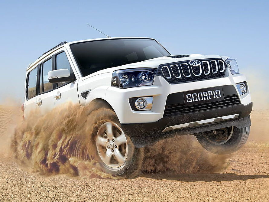 White Mahindra Scorpio SUV drifting on dusty desert terrain kicking up sand HD wallpaper