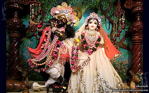 Radha Krishna Deities Playing Flute in Temple Altar with Floral Garlands HD wallpaper