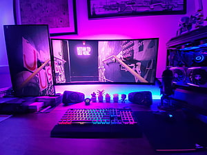 Vibrant Purple and Blue RGB Gaming Setup with Ultrawide Monitor and Mechanical Keyboard HD wallpaper