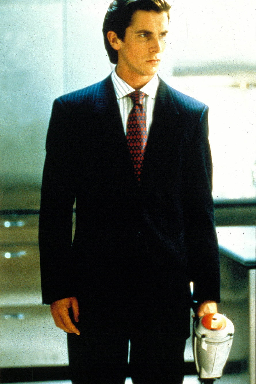 Patrick Bateman in a dark pinstripe suit holding a briefcase in a modern office setting, American Psycho's Patrick Bateman nailed 1980s businessman style, #patrick bateman HD phone wallpaper