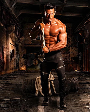 Tiger Shroff Shirtless Workout Scene Holding Rope in Dark Industrial Setting HD phone wallpaper