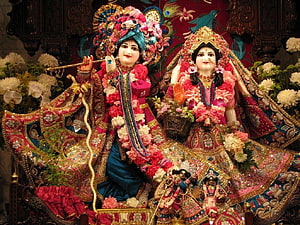 Radha Krishna idols adorned with flowers and jewelry in a temple setting HD wallpaper