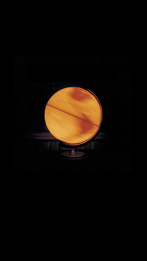 Glowing Orange Globe on Stand Against Dark Background HD phone wallpaper