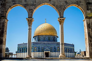 Dome of the Rock in Jerusalem framed by stone arches under a clear blue sky HD wallpaper