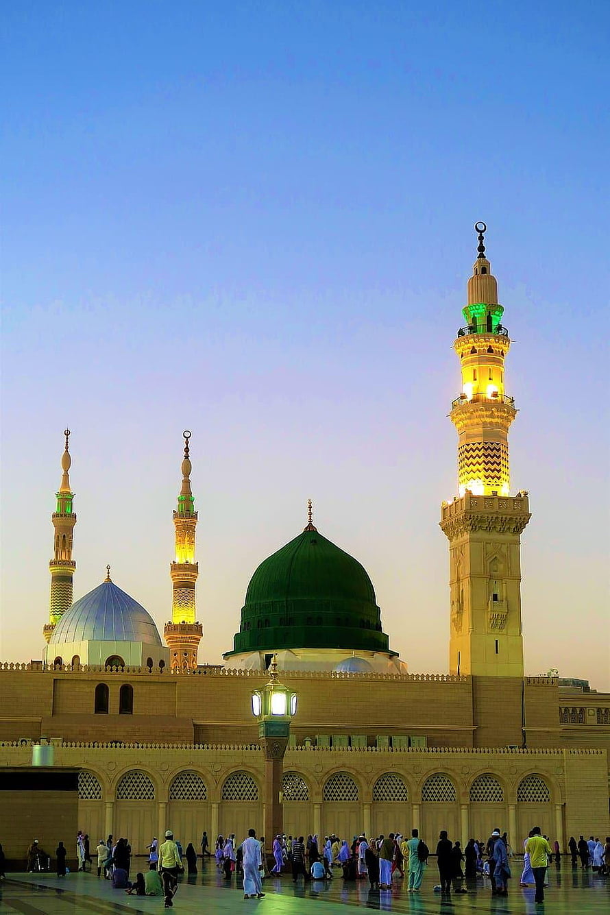 Al-Masjid an-Nabawi in Medina with the iconic Green Dome and illuminated minarets at dusk HD phone wallpaper