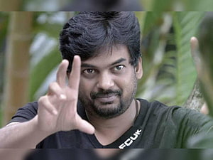 Actor Dhanush in a black t-shirt making a hand gesture outdoors HD wallpaper