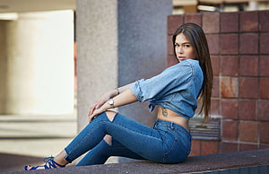 Young woman in denim shirt and ripped jeans sitting on a ledge, : women, sitting, torn jeans, denim shirt, portrait, tattoo, watch, long hair 2048x1321, sitting women HD wallpaper